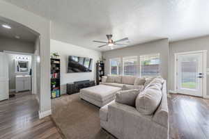 Living room with arched walkways, hardwood / wood-style floors, visible vents, and ceiling fan