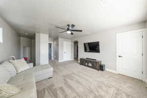 Carpeted living area with visible vents, a ceiling fan, baseboards, and arched walkways