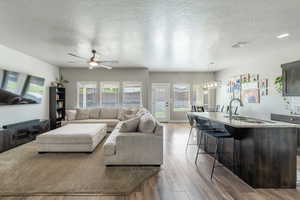 Living area with wood finished floors, visible vents, a textured ceiling, and ceiling fan
