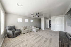 Living area featuring carpet flooring, baseboards, visible vents, and ceiling fan