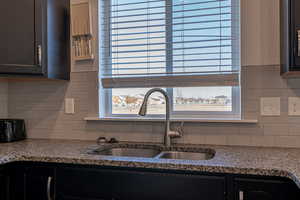 Kitchen with backsplash, stone countertops, a healthy amount of sunlight, and sink