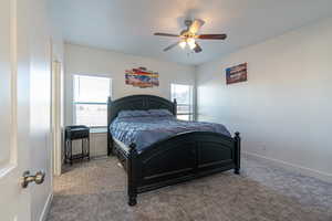 Carpeted bedroom featuring ceiling fan and multiple windows