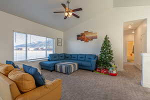 Carpeted living room with ceiling fan and vaulted ceiling