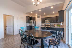 Dining room with light hardwood / wood-style flooring, a chandelier, and vaulted ceiling