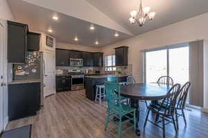 Dining space featuring hardwood / wood-style floors, a notable chandelier, lofted ceiling, and sink