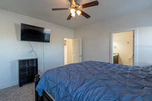 Carpeted bedroom with ceiling fan and ensuite bathroom