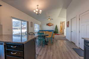 Dining area with ceiling fan with notable chandelier, dark hardwood / wood-style floors, and lofted ceiling