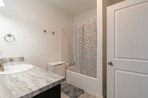 Bathroom with shower / bath combo with shower curtain, vanity, and tile patterned flooring