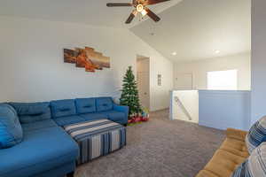 Carpeted living room featuring ceiling fan and vaulted ceiling