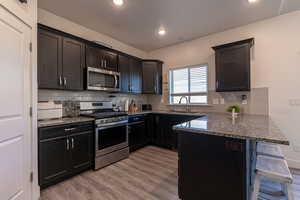 Kitchen featuring kitchen peninsula, sink, light wood-type flooring, and stainless steel appliances