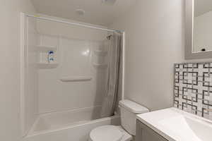 Full bathroom featuring shower / bath combination with curtain, vanity, a textured ceiling, and toilet