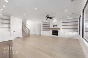 Unfurnished living room with ceiling fan, a fireplace, light hardwood / wood-style floors, and built in features