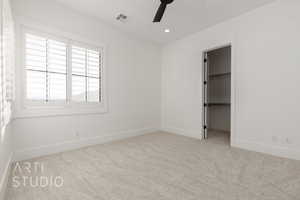 Unfurnished bedroom featuring light carpet, a spacious closet, a closet, and ceiling fan