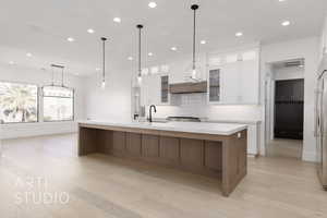 Kitchen with a large island, light hardwood / wood-style floors, and white cabinetry