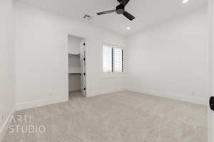 Unfurnished bedroom featuring a spacious closet, a closet, ceiling fan, and light carpet