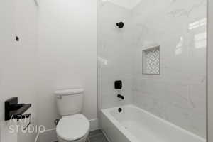 Bathroom with tile patterned floors, tiled shower / bath combo, and toilet