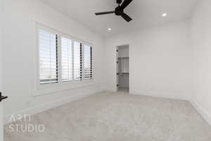 Unfurnished bedroom with a closet, light colored carpet, a spacious closet, and ceiling fan