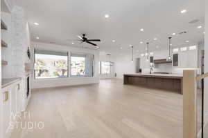 Kitchen with white cabinetry, ceiling fan, hanging light fixtures, decorative backsplash, and light wood-type flooring