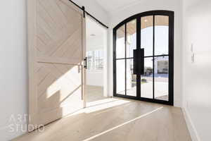 Doorway to outside with a barn door, hardwood / wood-style floors, and a healthy amount of sunlight