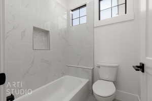 Bathroom featuring tiled shower / bath and toilet