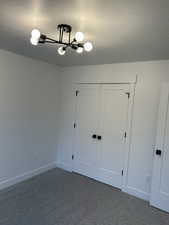 Unfurnished bedroom featuring a closet, a textured ceiling, and dark colored carpet