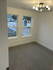 Empty room with carpet, plenty of natural light, an inviting chandelier, and a textured ceiling