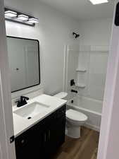 Full bathroom with vanity, wood-type flooring, bathtub / shower combination, and toilet