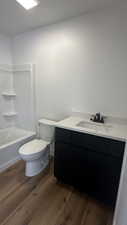 Full bathroom with hardwood / wood-style flooring, shower / bath combination, toilet, and vanity