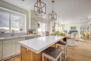 Kitchen featuring sink, decorative light fixtures, dishwasher, light hardwood / wood-style floors, and a kitchen island