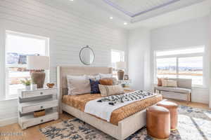 Bedroom featuring a raised ceiling, wood walls, light hardwood / wood-style flooring, and wooden ceiling