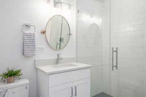 Bathroom featuring vanity, toilet, and a shower with shower door