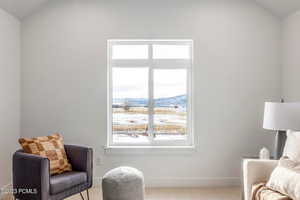 Living area with a mountain view, light carpet, and vaulted ceiling