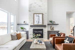 Living room with a high ceiling, dark hardwood / wood-style flooring, a mountain view, wooden walls, and a fireplace