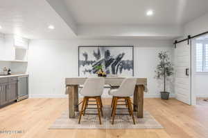 Dining room with a barn door and light hardwood / wood-style flooring