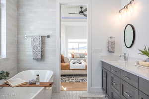 Bathroom featuring tile patterned flooring, vanity, ceiling fan, and a tub