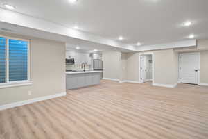 Unfurnished living room featuring sink and light hardwood / wood-style flooring