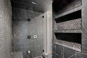 Bathroom featuring a tile shower and tile walls