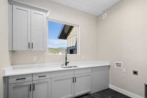 Laundry area with cabinets, sink, washer hookup, and hookup for an electric dryer