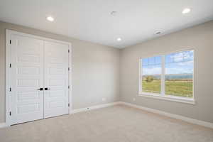 Unfurnished bedroom with light carpet and a closet