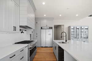 Kitchen featuring light stone countertops, sink, stainless steel appliances, and light wood-type flooring