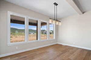 Unfurnished dining area featuring a wealth of natural light, beamed ceiling, a mountain view, and light wood-type flooring