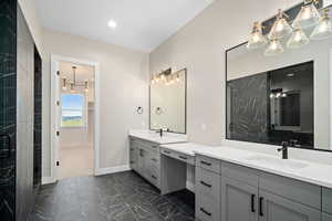 Bathroom featuring a notable chandelier, vanity, and an enclosed shower