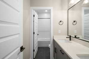 Full bathroom with tiled shower / bath, tile patterned flooring, vanity, and toilet