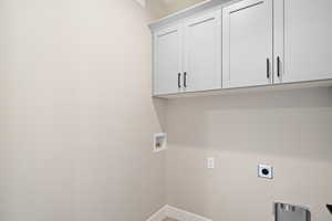 Clothes washing area with hookup for a washing machine, cabinets, and hookup for an electric dryer