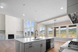 Kitchen featuring dishwasher, sink, a kitchen island with sink, and light hardwood / wood-style flooring