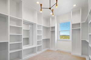 Spacious closet featuring carpet and a notable chandelier