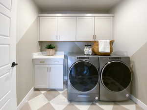 Clothes washing area featuring separate washer and dryer and cabinets