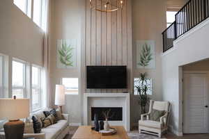 Family room with hardwood / wood-style flooring, a notable chandelier, a fireplace, and a high ceiling