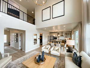 Family room featuring light wood-type flooring, a towering ceiling, and an inviting chandelier