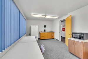 Kitchen featuring white fridge and light colored carpet